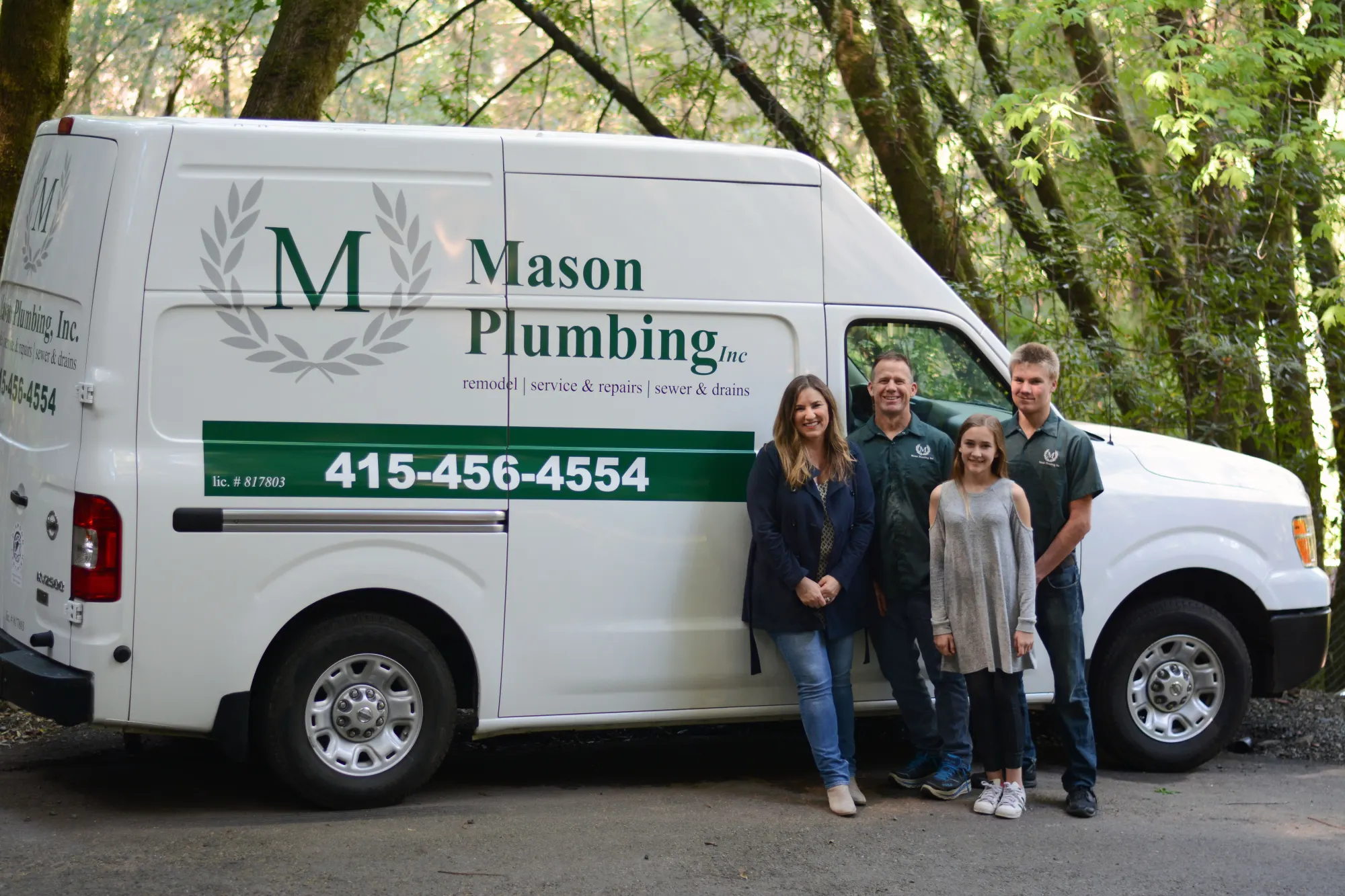 The Mason family standing beside a Mason Plumbing van among trees